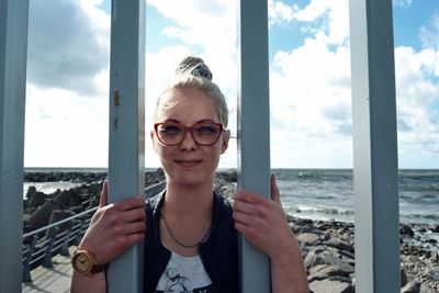 Portrait of young woman standing by sea against sky