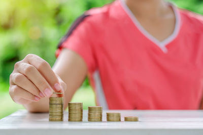 Midsection of woman stacking coins on table
