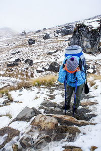 Tired young woman with backpack and trekking poles on hike in mountains of nepal in winter. resting 