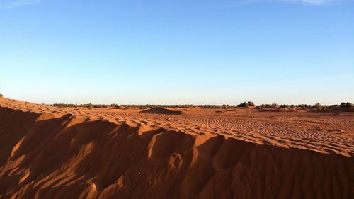 Sand dunes in desert against clear blue sky