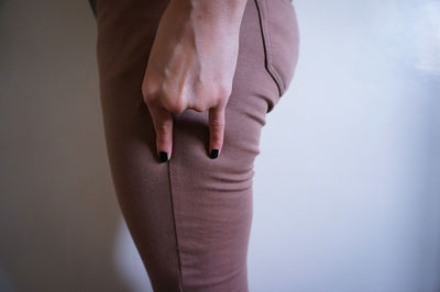 Midsection of woman gesturing shaka sign against white wall