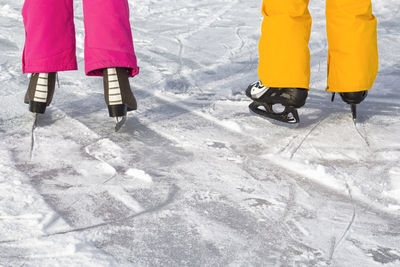 Low section of people wearing ice skates on snow