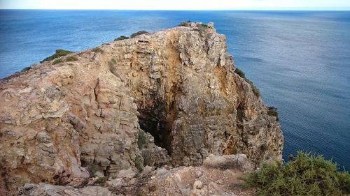 Rock formation by sea against sky