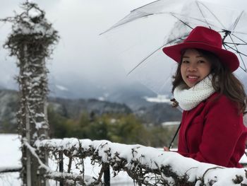 Portrait of smiling young woman standing with umbrella during winter