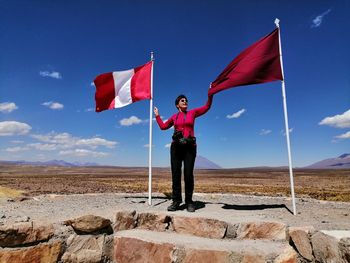 Rear view of man standing on retaining flag against sky