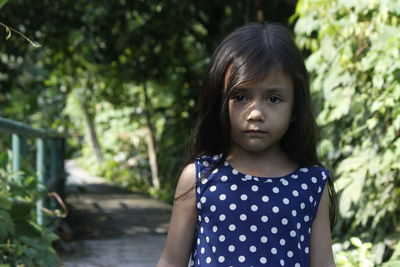 Portrait of cute girl standing against trees in park