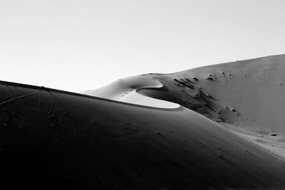 Man on sand dune against clear sky