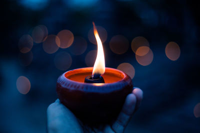 Close-up of hand holding lit candle