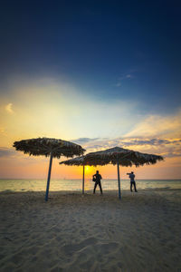 Silhouette people on beach against sky during sunset