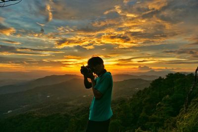 Full length of man photographing at sunset