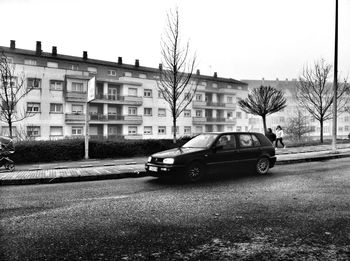 Cars on road by buildings in city against clear sky