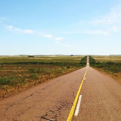 Road amidst field against sky