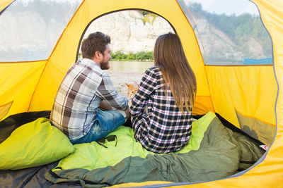 Rear view of couple sitting at tent