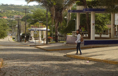 Woman with umbrella walking on palm trees