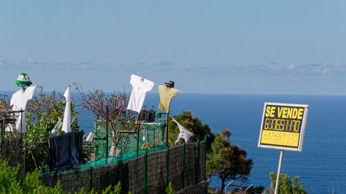 Information sign by sea against clear sky