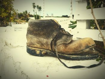 Close-up of shoes on sand at beach against sky