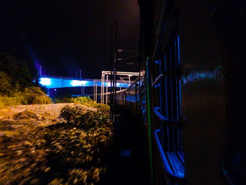 Train at illuminated railroad station against sky at night