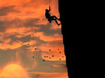 Silhouette people on rock against sky during sunset