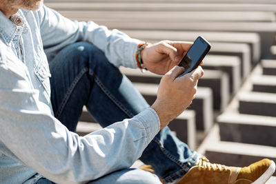 Midsection of man using mobile phone