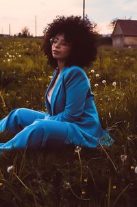 Young woman with eyes closed sitting on grass during sunset