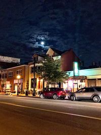 Cars on illuminated city street at night