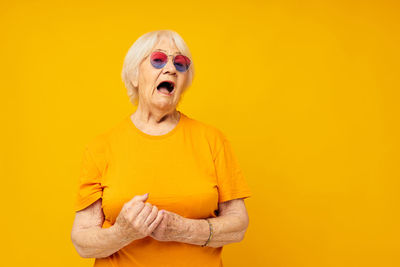 Portrait of young woman against yellow background