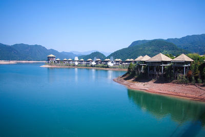 Scenic view of lake by buildings against clear blue sky