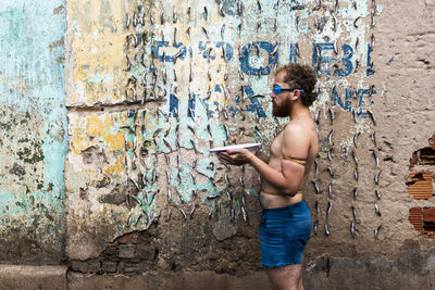 Full length of young man holding a bowl of water against wall