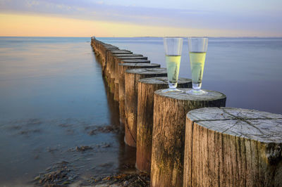 Wooden posts on pier over sea against sky