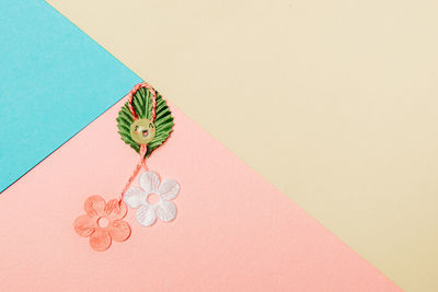 One martisor made from flowers, a petal and a smiley face lies on the left on a colorful background 