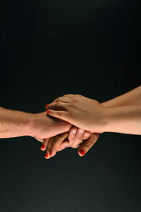 Midsection of couple holding hands against black background