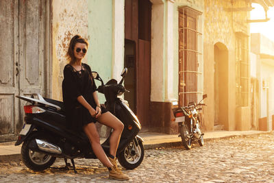 Side view of woman using mobile phone while sitting on street