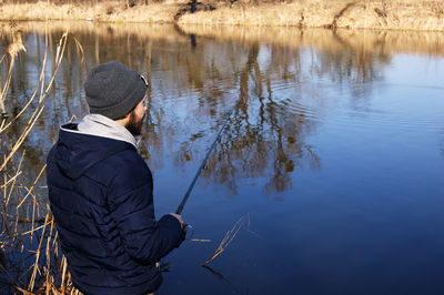 Rear view of man standing by lake