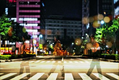 Illuminated street amidst buildings in city at night