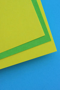 High angle view of yellow paper over blue background