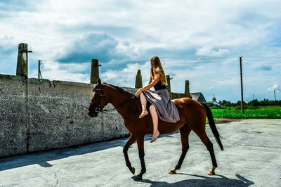 Woman sitting on horse against sky