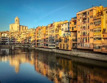 Buildings by river against sky in city