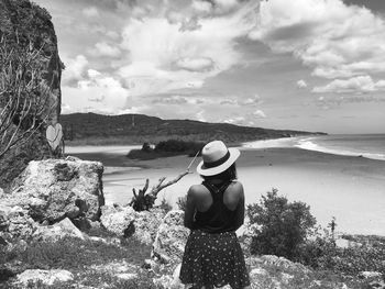 Rear view of woman standing by sea against sky
