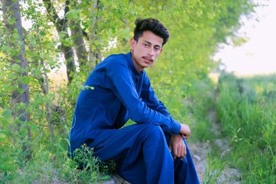 Portrait of young man sitting on field