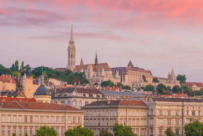 Buildings in city against sky during sunset