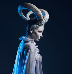 Young woman with horns looking away against black background