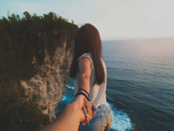 Hand of man holding woman at beach during sunset