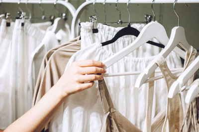 Sustainable fashion, slow fashion. close up shot of female hand taking clothing rack with natural