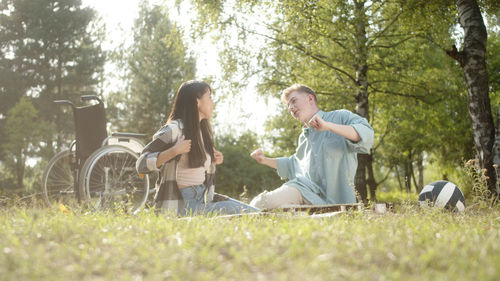 Side view of couple sitting on field