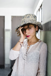 Close-up of beautiful woman wearing hat standing by wall