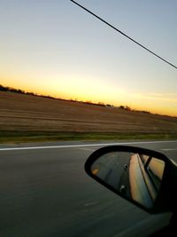 Car on road against clear sky during sunset