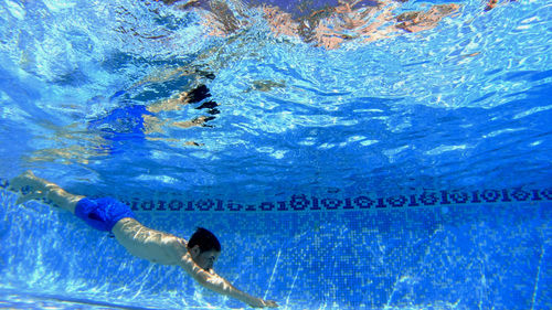 Underwater view of man diving into swimming pool
