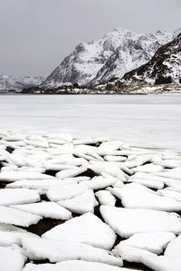 Scenic view of frozen lake by snowcapped mountains against sky