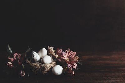 Easter card with copy space, wooden table background. easter eggs in nest, pink flowers, feathers