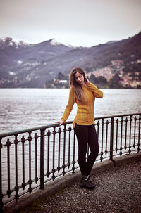 Woman standing by railing against lake